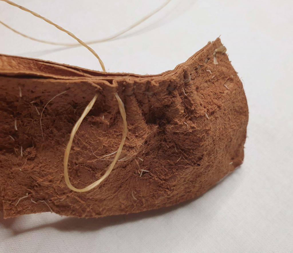 Fotografi av at to deler skinn blir sydd sammen med et mellomlegg som er brettet dobbelt. For hvert sting får det fremste skinnstykket en fold, slik at det dannes rynker.