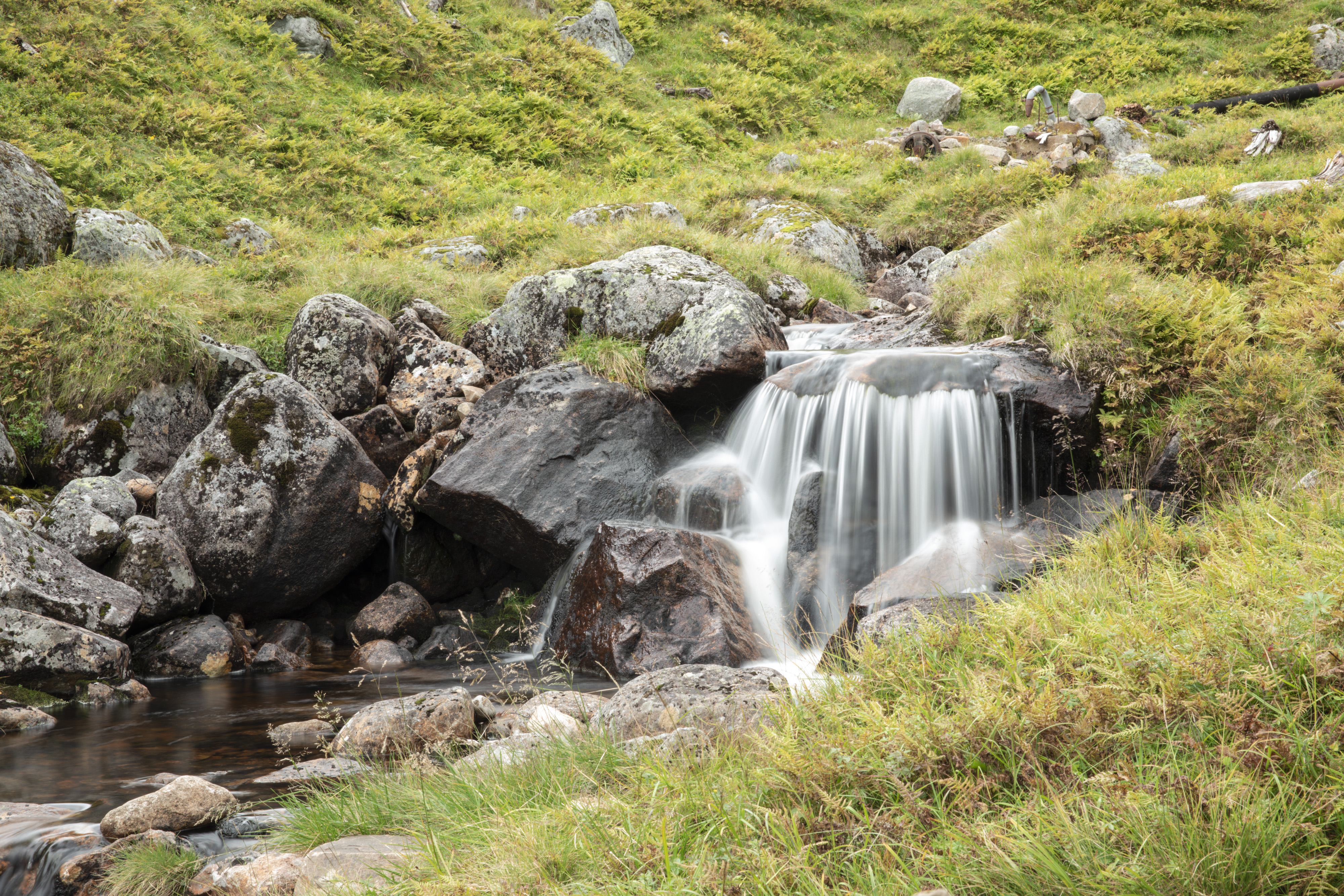 Fjellandskap med en liten foss som renner ut i en bekk. Foto.