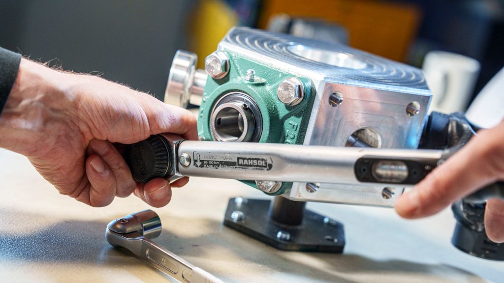 To hender som skrur på en skrue med et verktøy. Foto.