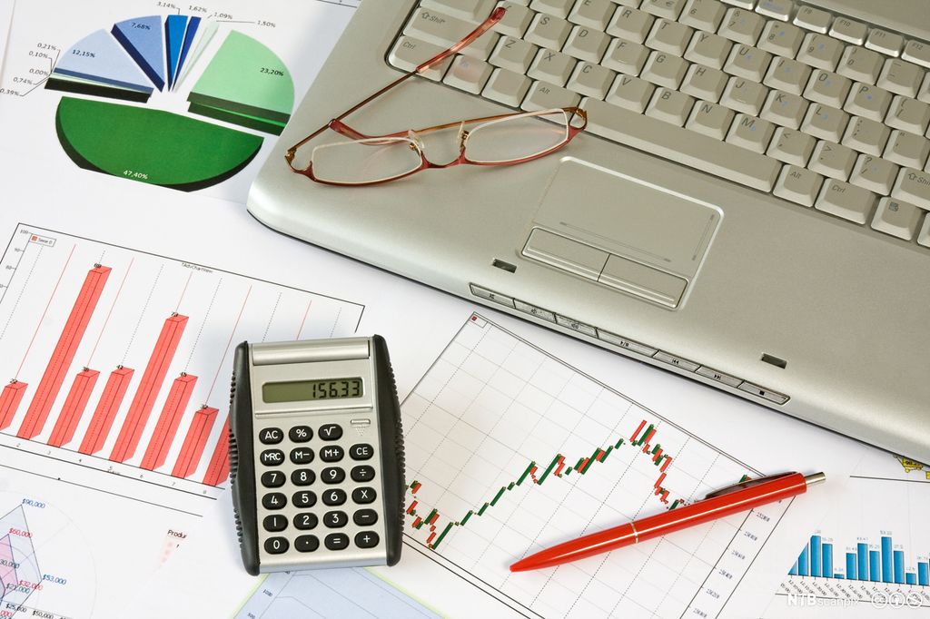 Ark med statistikk og diagrammer, en bærbar PC, en penn og en kalkulator sett ovenfra. Foto.