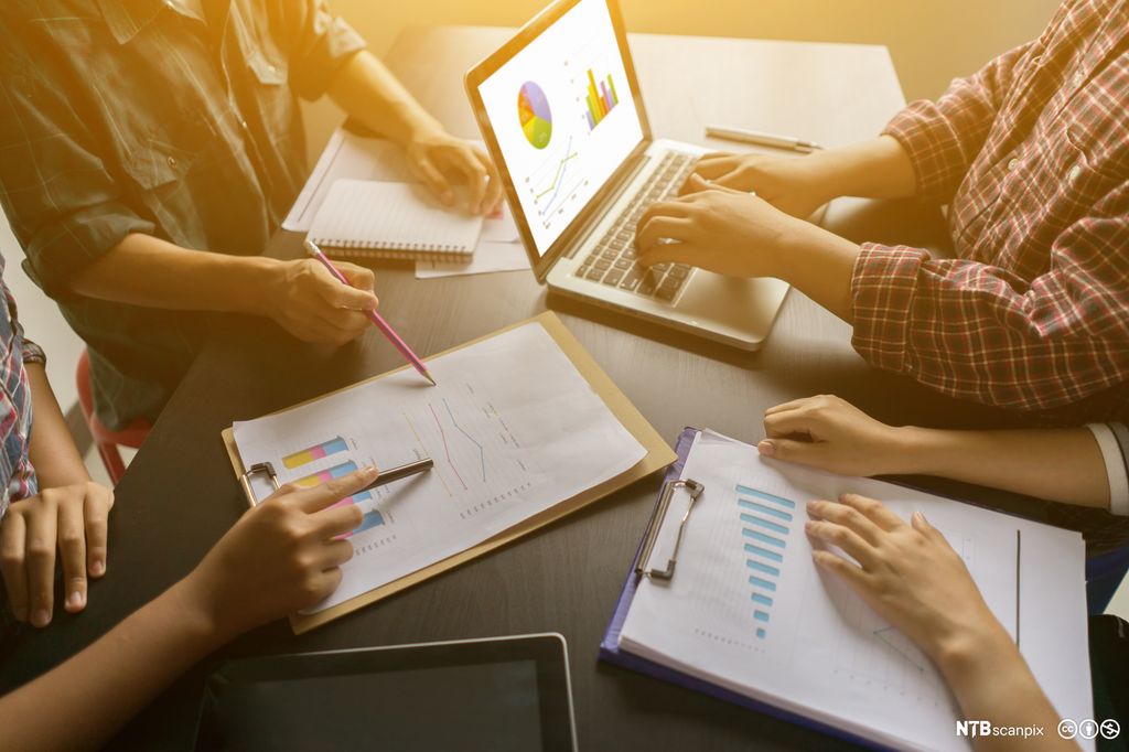 Gruppe mennesker samarbeider om statistikker. Bilde.