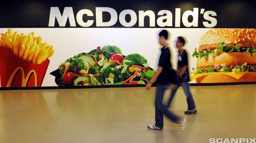 To personer som passerer et McDonald-skilt. Fotografi.
