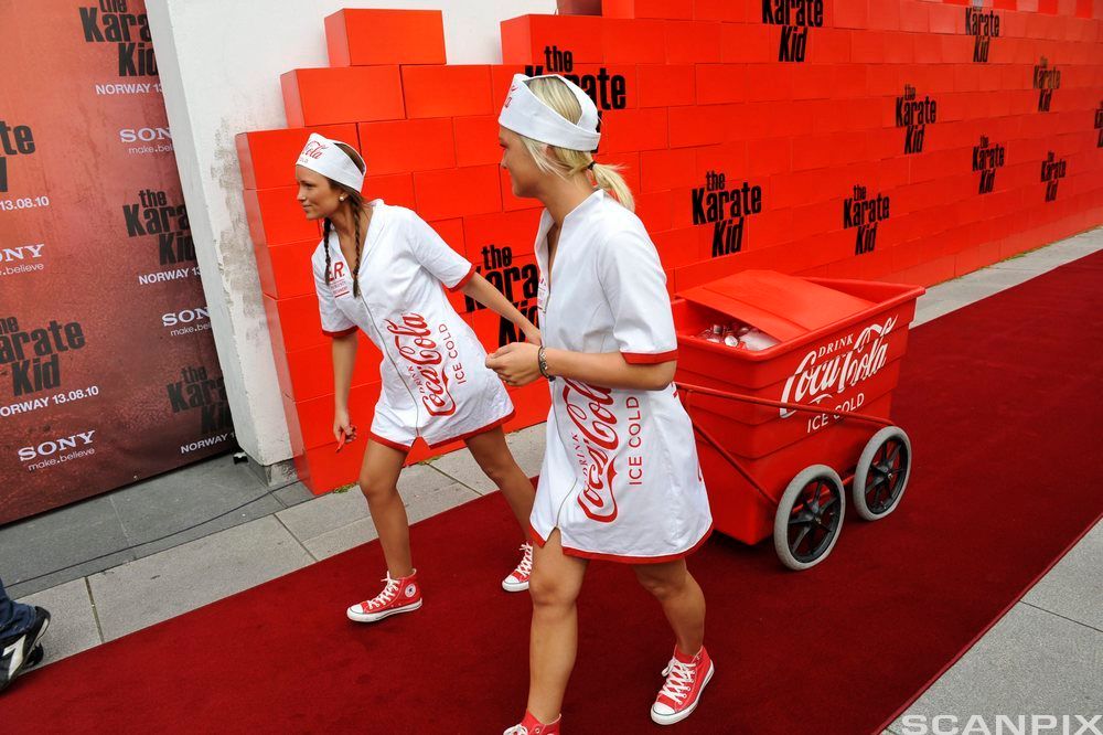 To jenter markedsfører og deler ut vareprøver av Coca-Cola under en filmpremiere i Fredrikstad. Foto. 