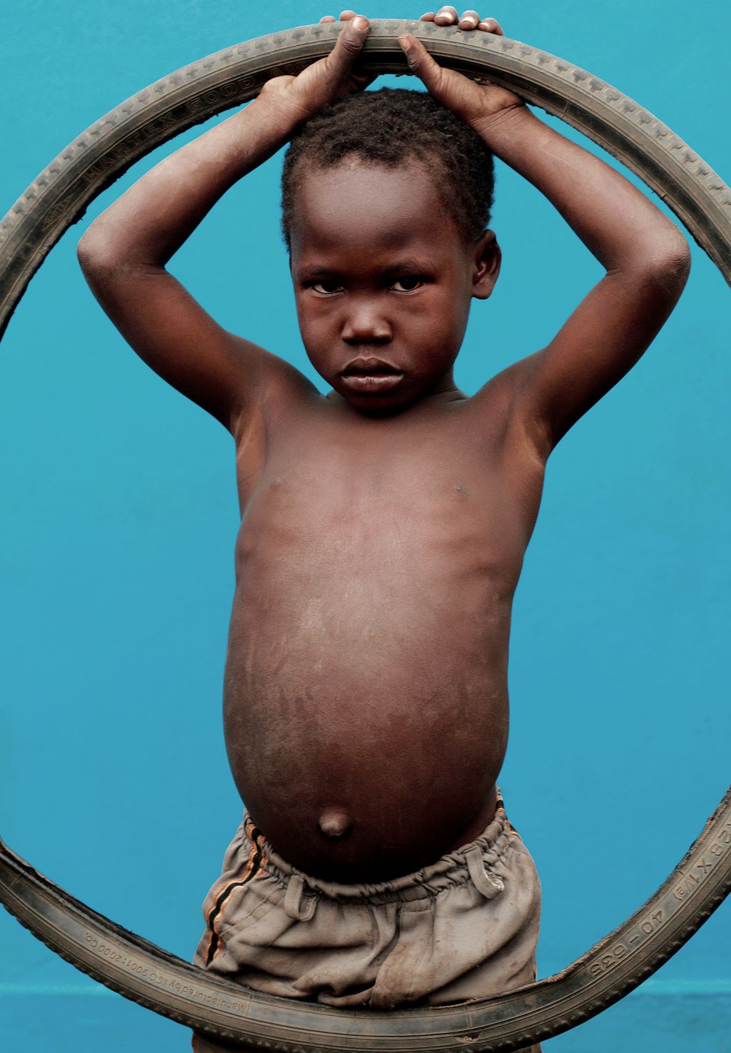 Ein liten mørkhuda gut held opp eit sykkeldekk. Foto.