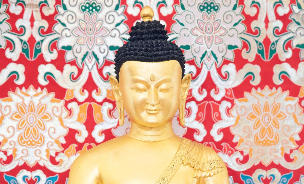 Gullfarget hode og skuldre på en buddhastatue. Foto.