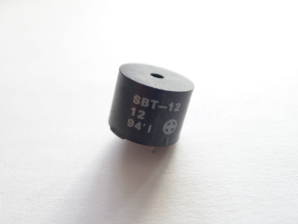 Elektrisk komponent forma som en sylinder. Den har et sirkelforma hull i midten og to tilkoplingspunkter på undersida. Foto.