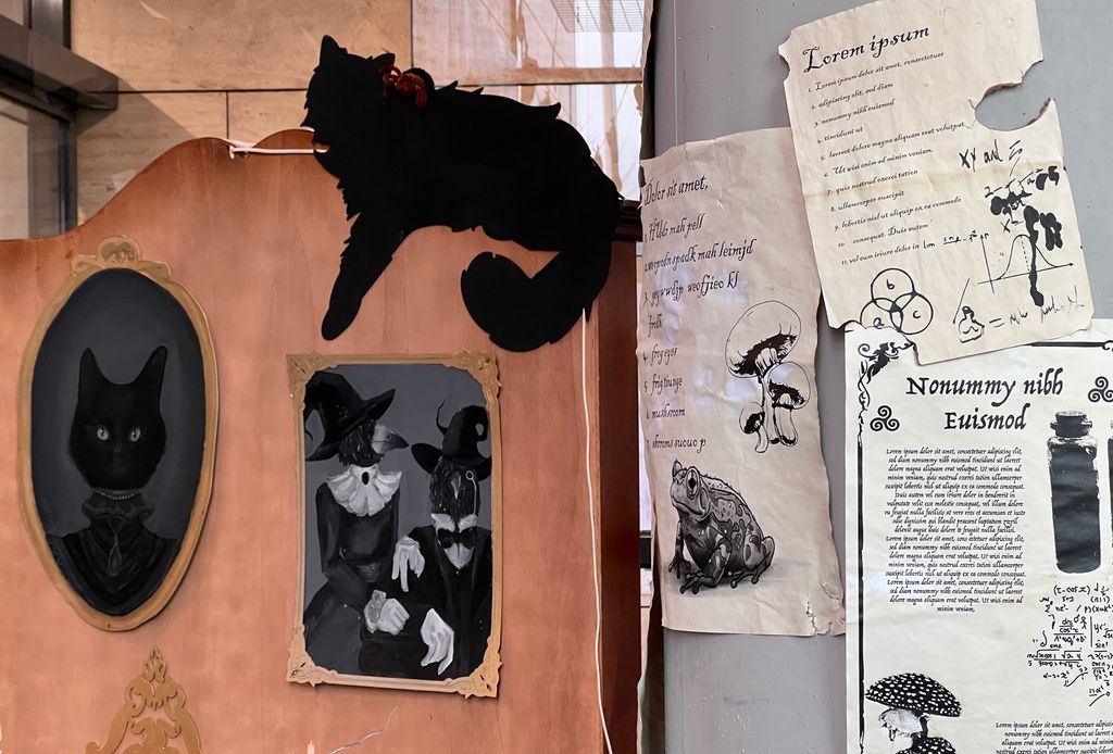Katte- og heksemotiver er hengt opp som dekor sammen med latinske tekster som har illustrasjoner av sopper og en frosk. Foto.