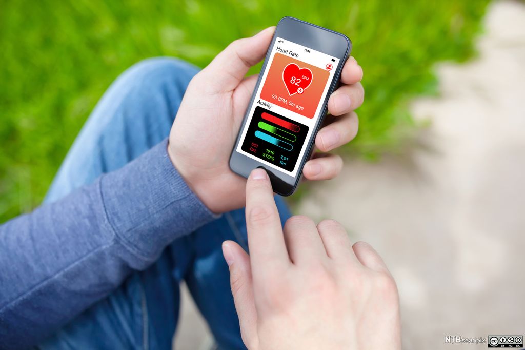 Person som sitter og ser på en helseapp på mobilen. Foto.