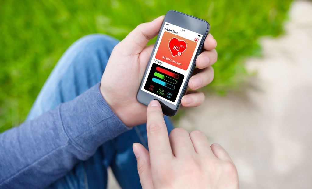 Ein person held ein mobiltelefon som viser ein helse-app på skjermen. Foto.