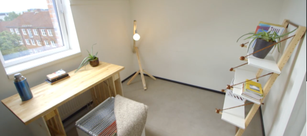 Hybel med pult, krakk, lampe og hylle. Foto.