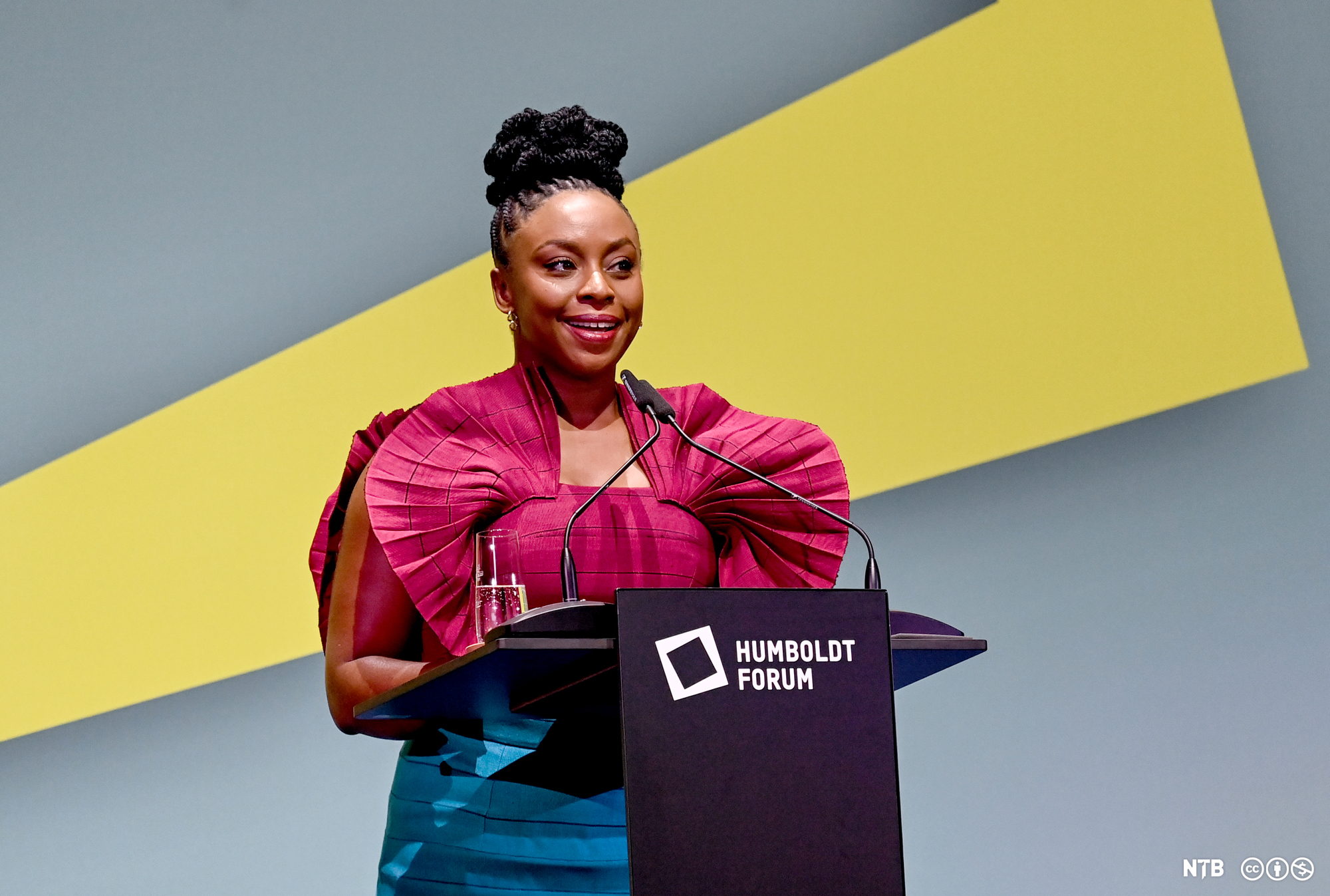 Den unge forfatteren Chimamanda Ngozi Adichie står på talerstolen. Hun har på seg en sjokkrosa bluse. Foto.