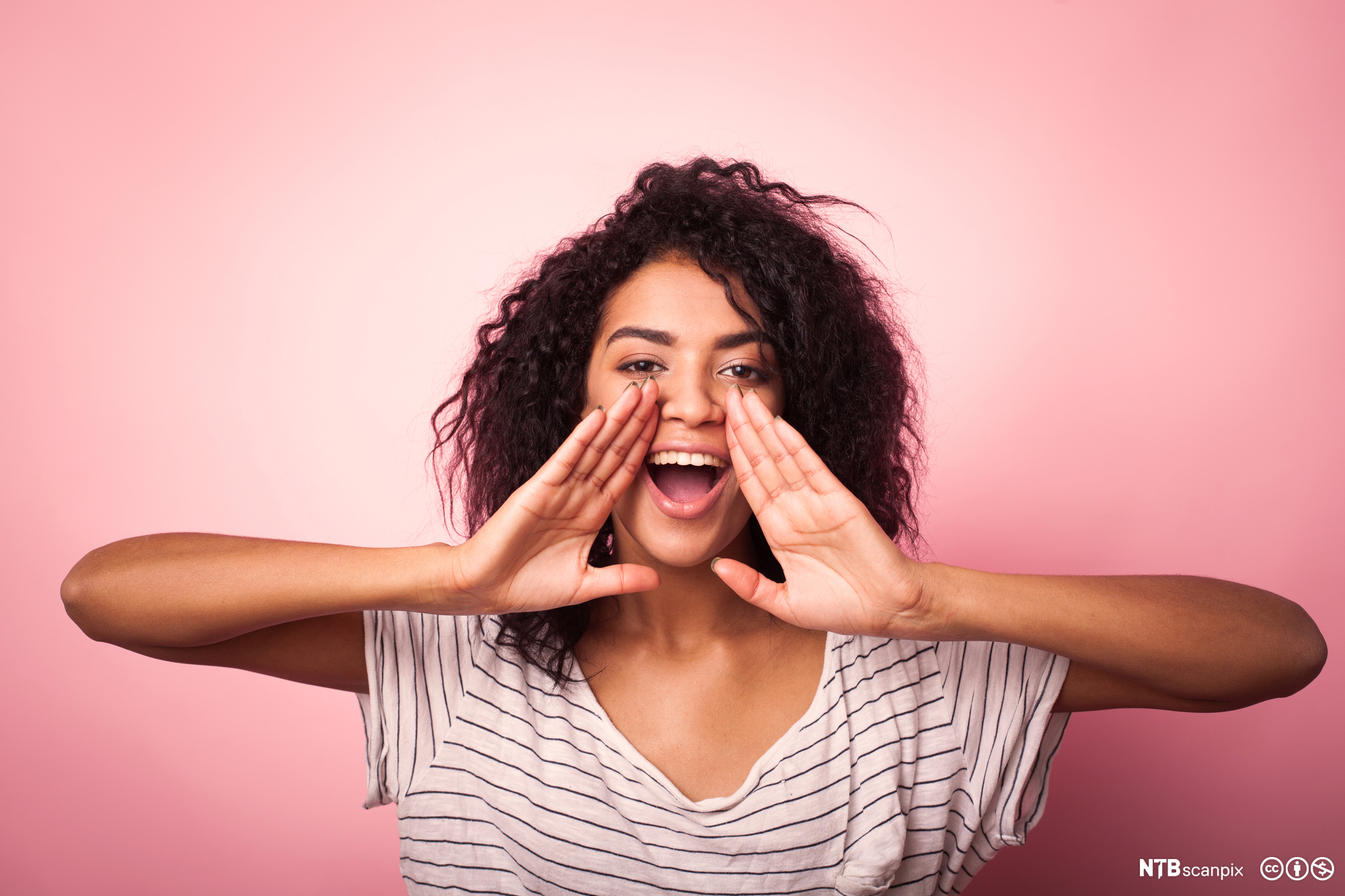 Ei jente holder hendene foran munnen slik man kan gjøre når man roper. Foto.