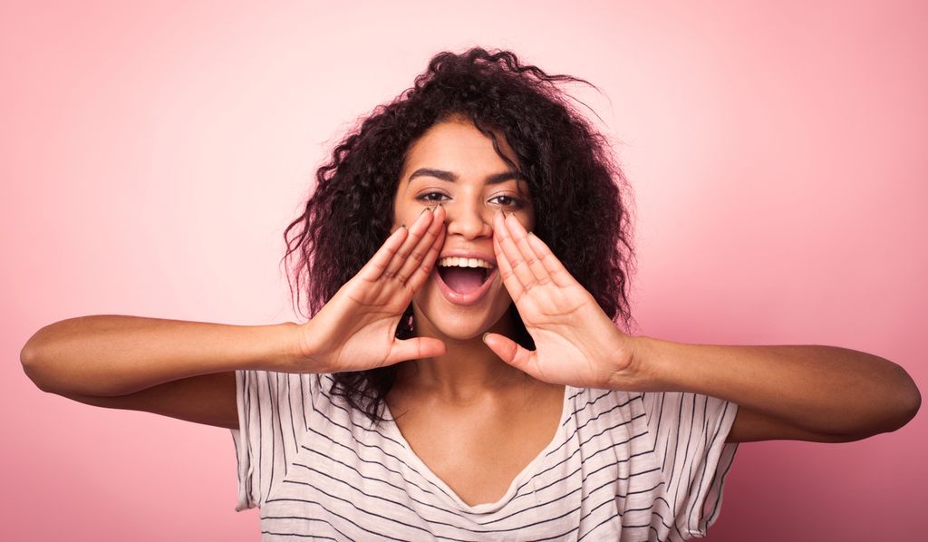 Ei jente holder hendene foran munnen slik man kan gjøre når man roper. Foto.