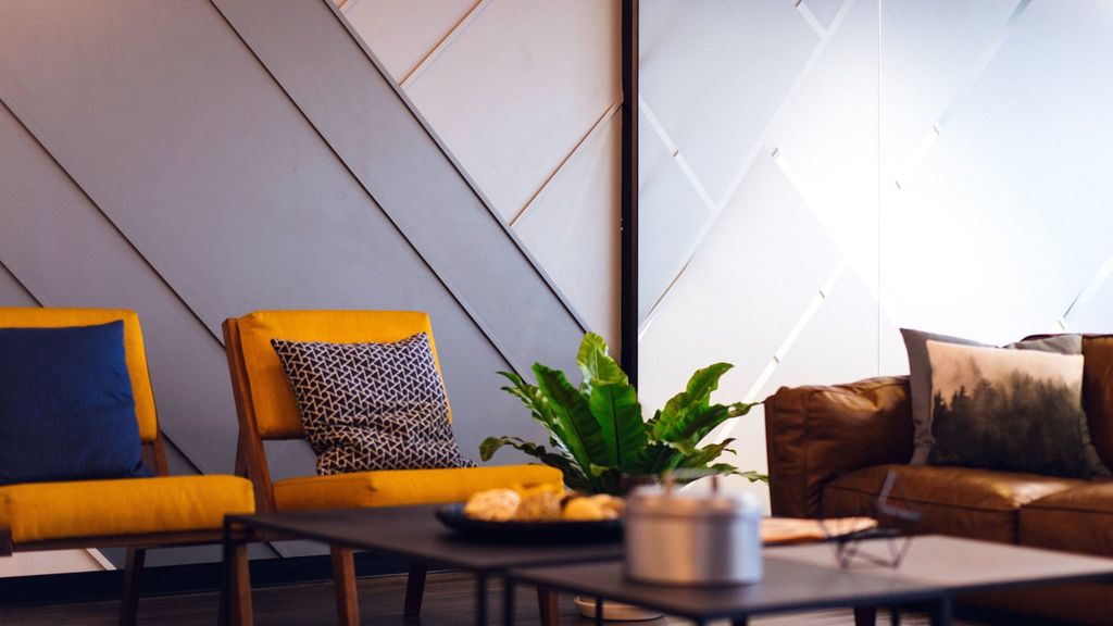 Sittegruppe med oransje stol med pute i kontrastfarge. Foto.