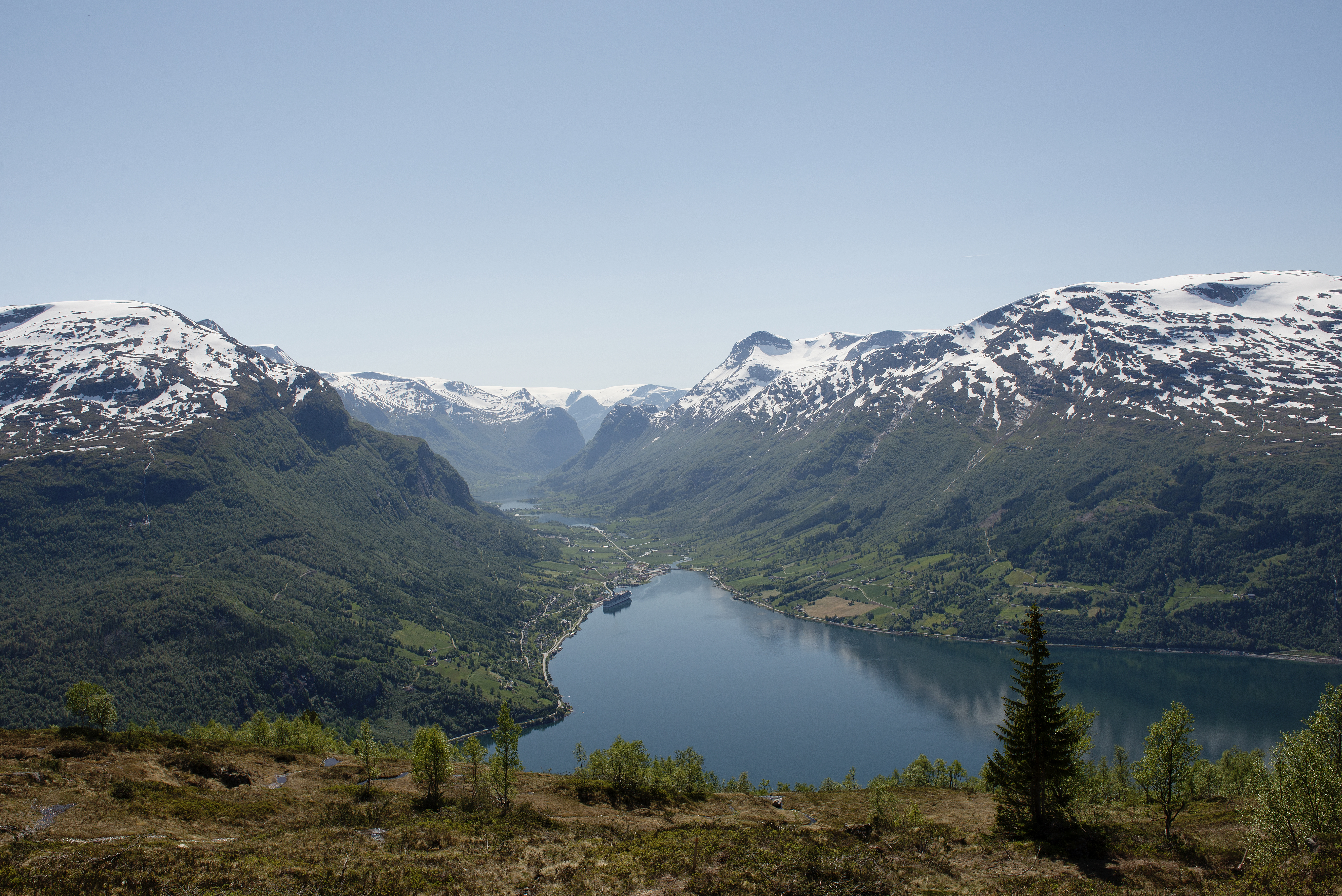 Landskap med høge fjell og ein dal imellom. Ein fjord strekker seg inn mot dalen. Foto.