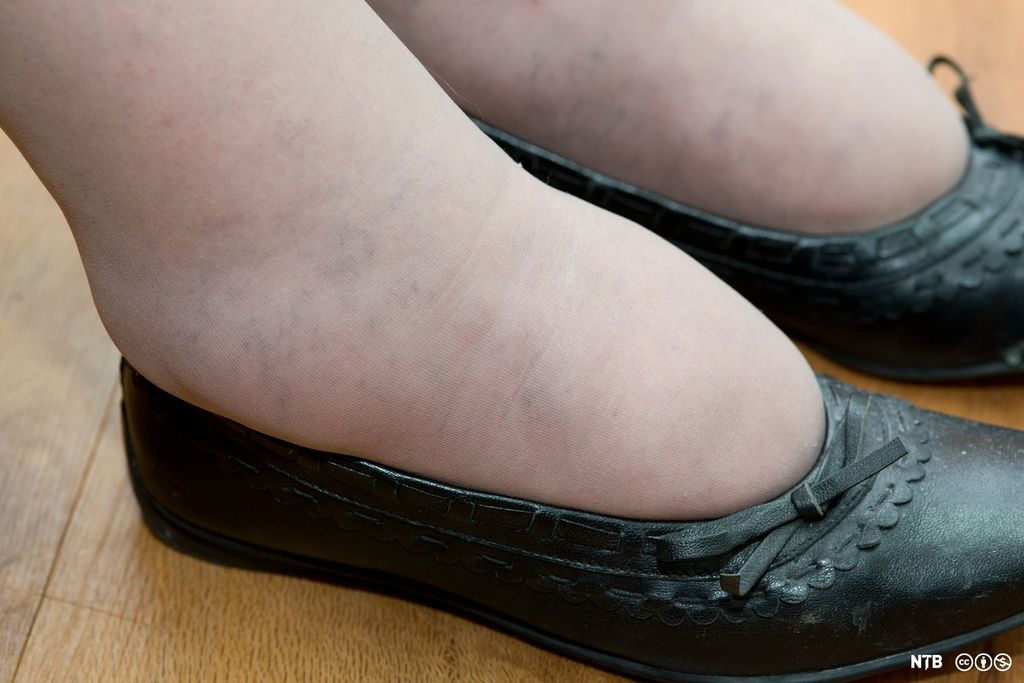 Et par hovne dameføtter i svarte, lave sko. Foto. 