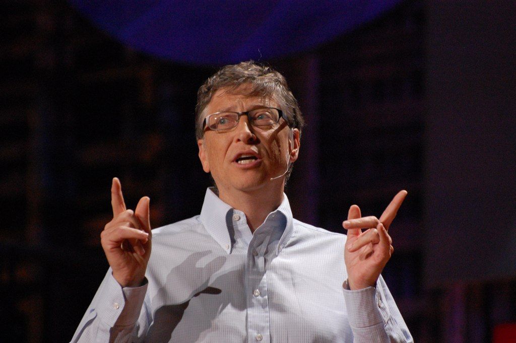 Close-up of Bill Gates, gesturing with his hands while talking to an audience. Photo.
