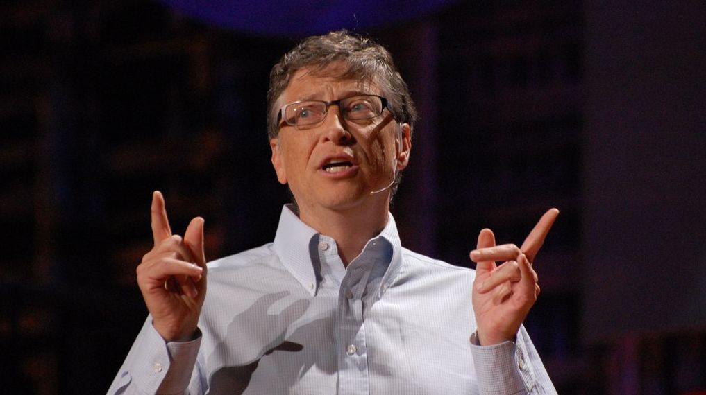 A close-up of Bill Gates, gesturing with his hands while talking to an audience. Photo.