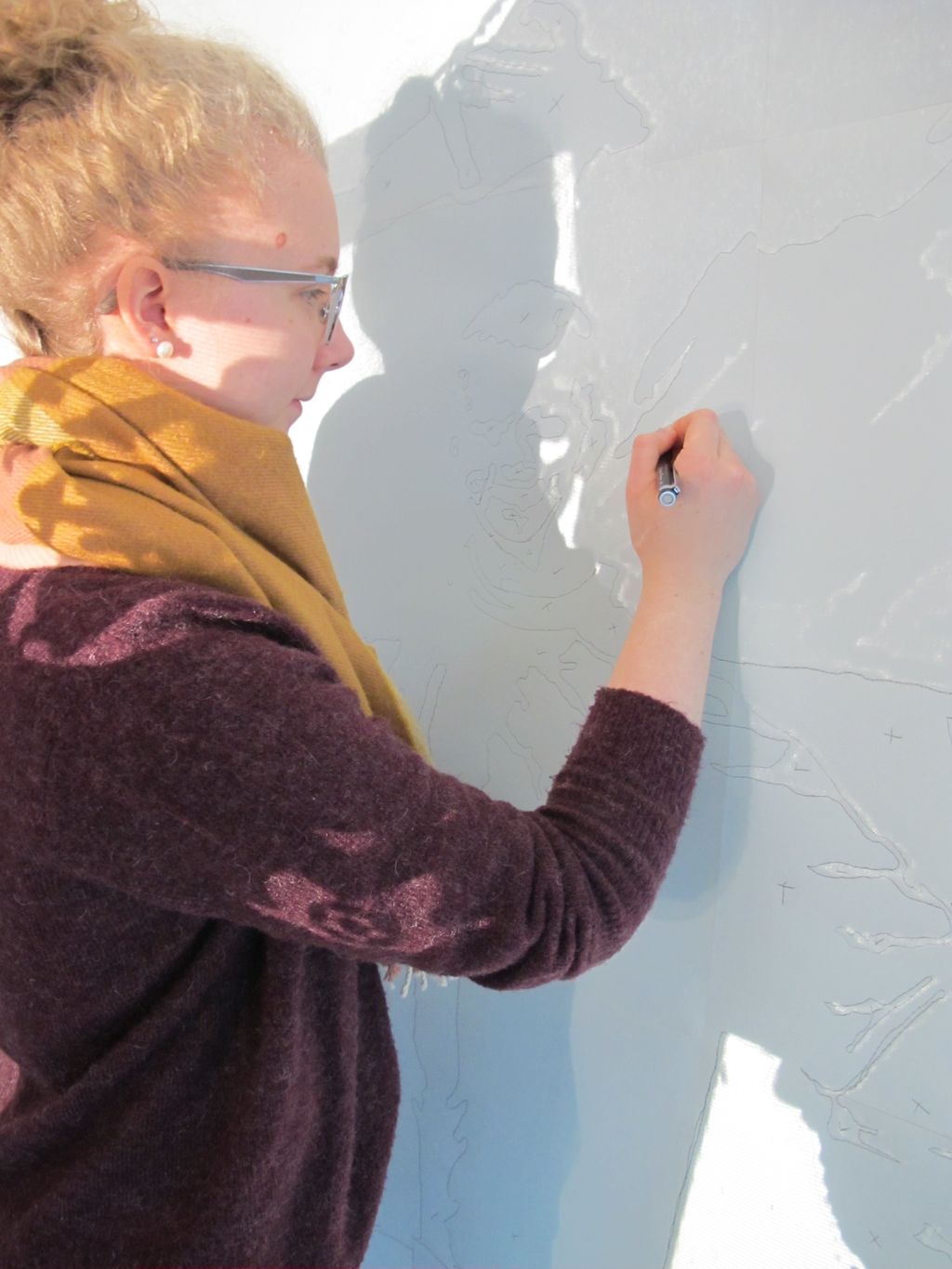 Elev tegner på en vegg i lyset fra en overheadprojektor. Foto.