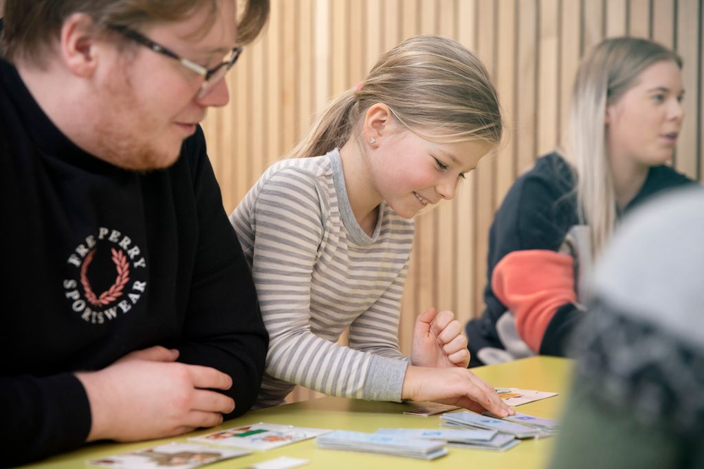 En voksen barne- og ungdomsarbeider spiller spill med ei jente. Foto.