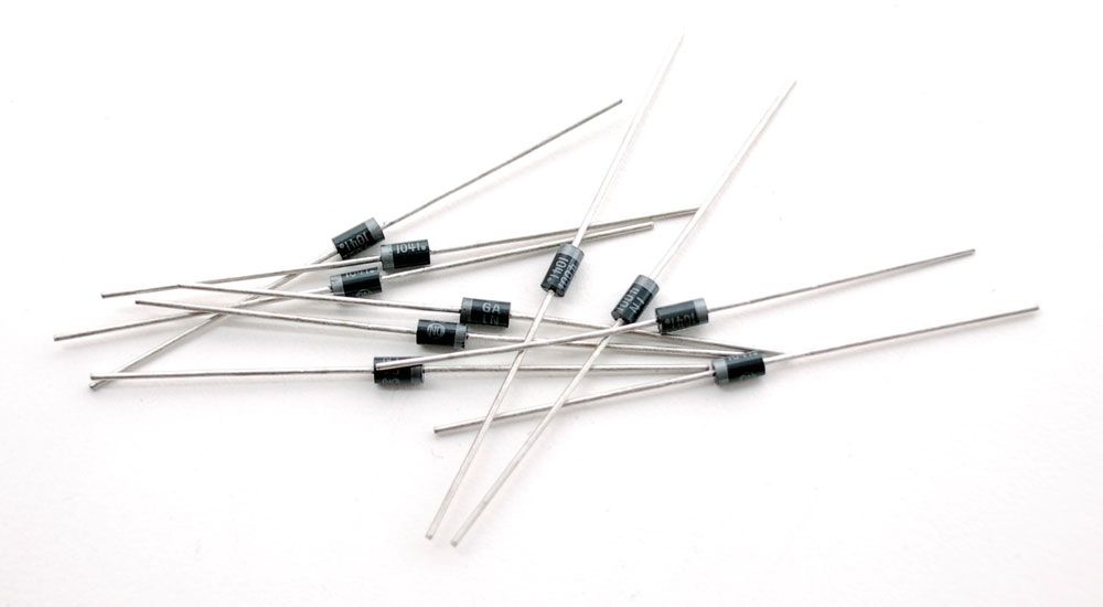 Ti dioder som ligger i en haug. Diodene er svarte, med ei grå stripe rundt den ene enden. De har to tilkoplingsbein, ett i hver ende. Foto.