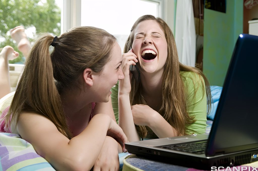 To jenter som ler framfor ein pc. Foto. 