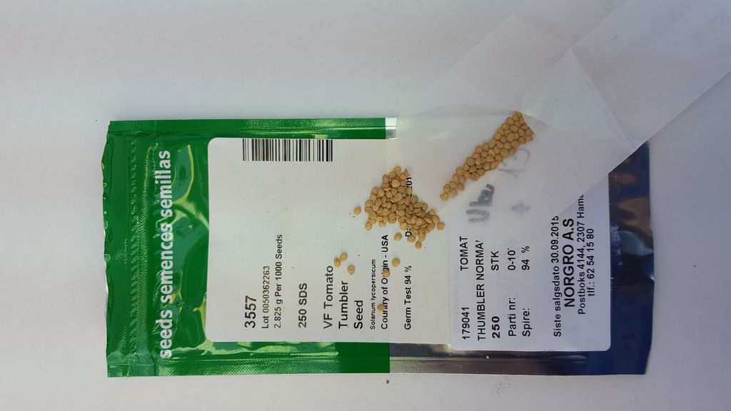 Pakke med tomatfrø, små tomatfrø ligger oppå pakken. Foto.