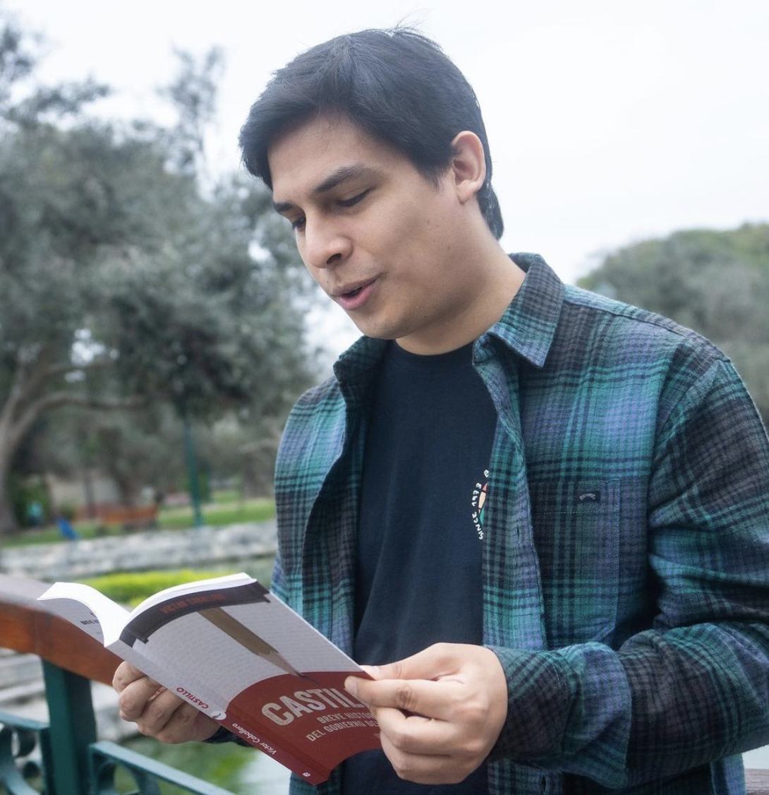 Ung mann med rutete skjorte blar i ei bok. Foto.