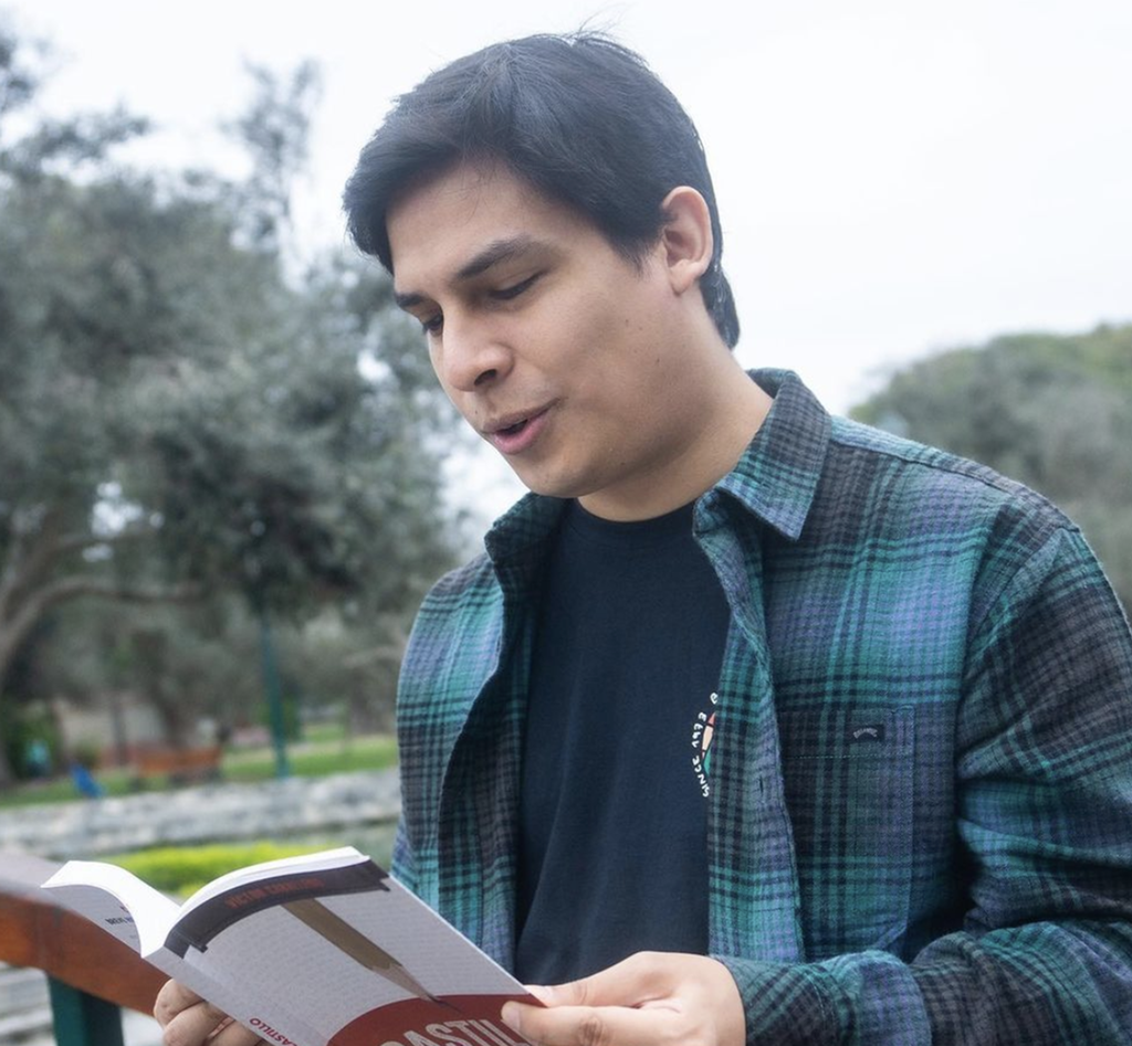 Ung mann med rutete skjorte blar i ei bok. Foto.