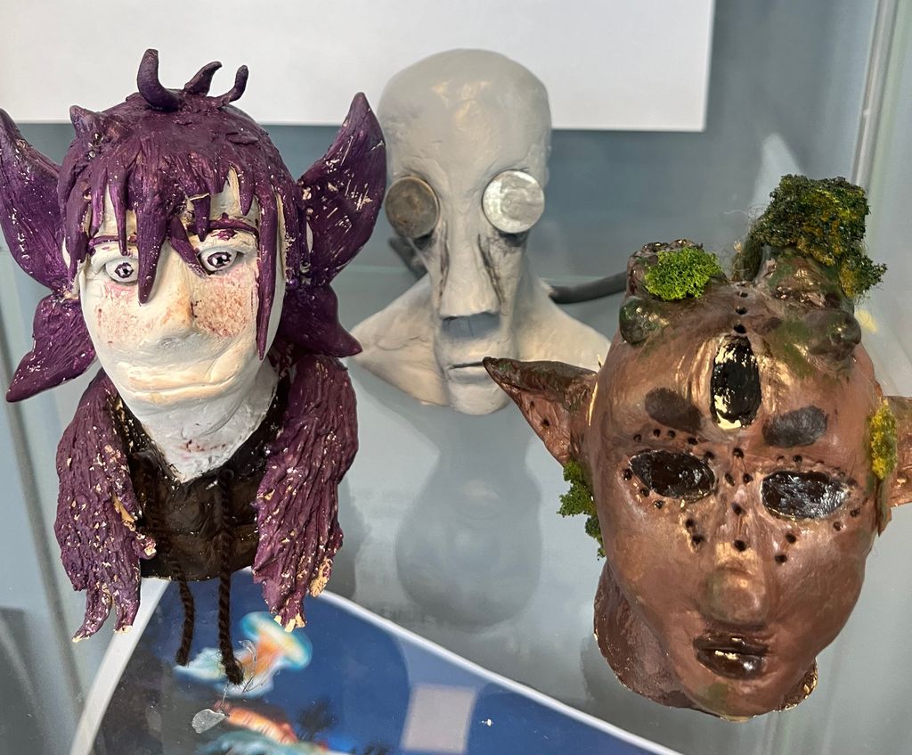 Hodene til tre fantasifigurer står utstilt. De er utformet i leire og malt. Foto.