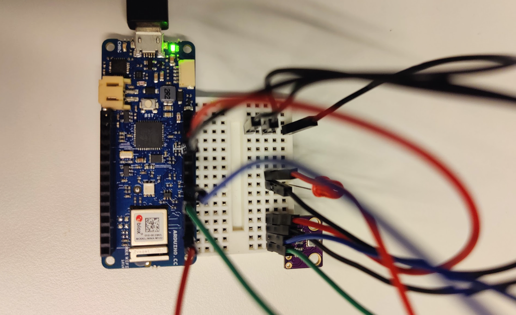 Mikrokontroller og sensor kopla sammen med ledninger via et koplingsbrett. En rød diode er kopla til koplingsbrettet. Foto.