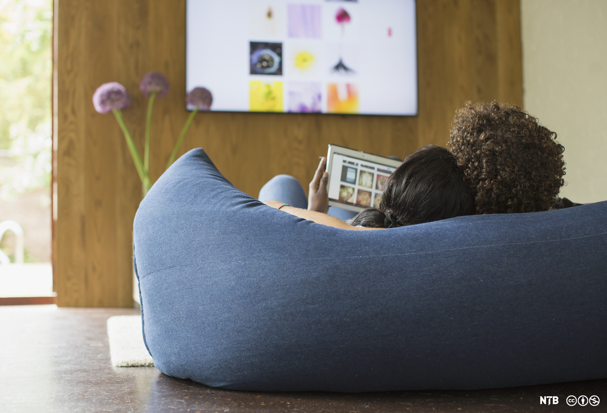 Young couple relaxing streaming photos from digital tablet to TV. Photo.