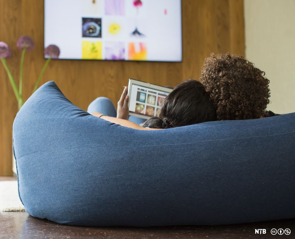 Young couple relaxing streaming photos from digital tablet to TV. Photo.