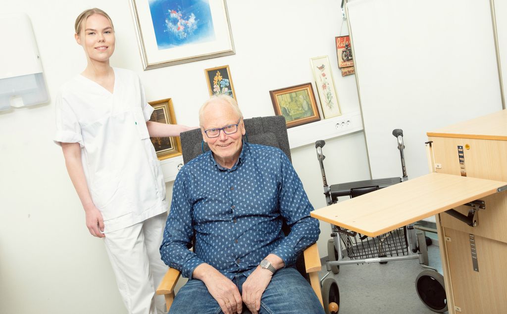 Kvinnelig helsefagarbeider med pasient som sitter i en stol. Foto.