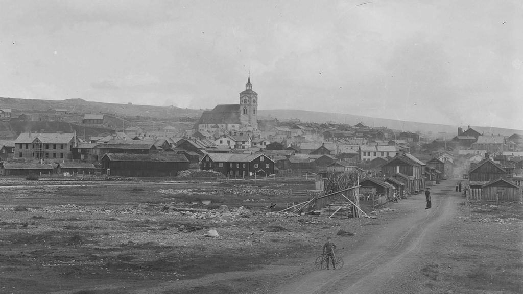Gate, kirke og hus i Røros. Vi ser noen mennesker i bildet. Foto.