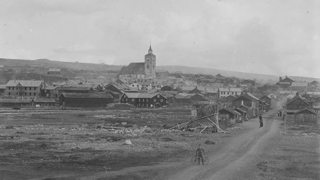 Gate, kirke og hus i Røros. Vi ser nokre menneske i biletet. Foto.
