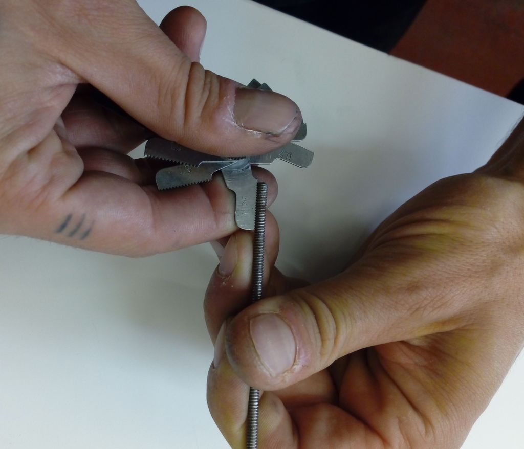 To hender som holder en skrue og et måleverktøy. Foto.