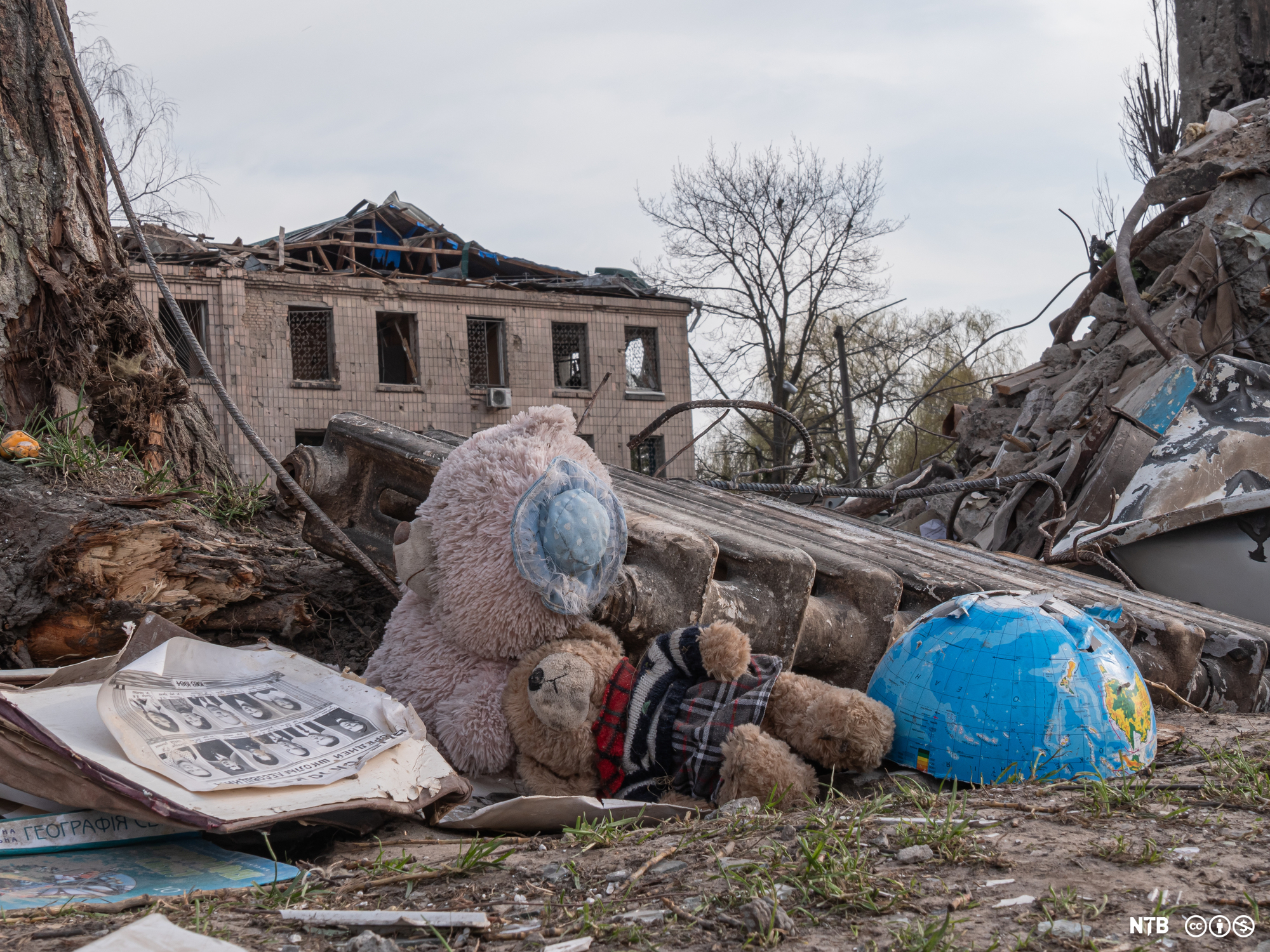 Photo: Buildings destroyed by bombs. In the foreground we see two teddy bears and half a globe. 