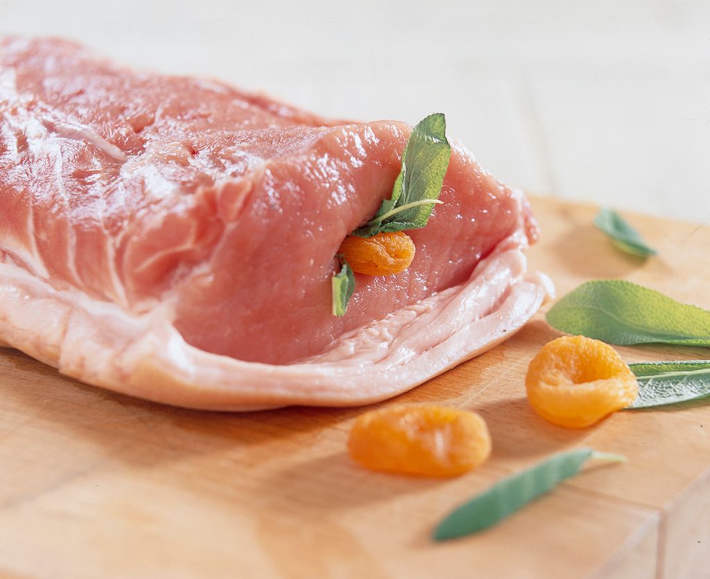 En svinekam fylt med aprikoser og salvie ligger på ei fjøl. Foto.