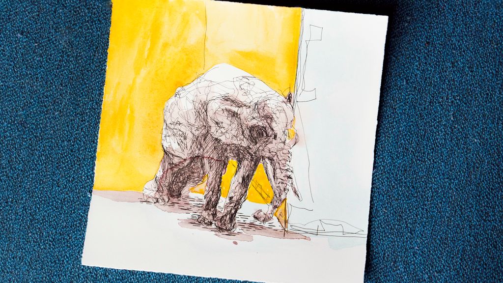 Tegning av en elefant mot en gul vegg. Foto.