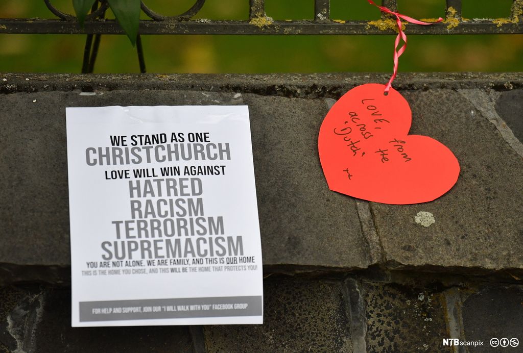 En plakat og et rødt hjerte med tekst som fordømmer terrorisme og rasisme. Foto.