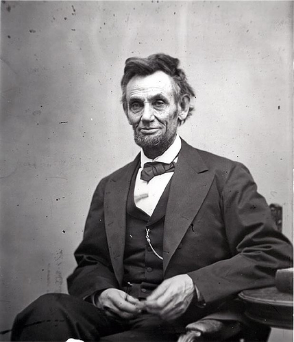Photo: Abraham Lincoln. We see an older man with a thin face, a beard, and ruffled hair. 