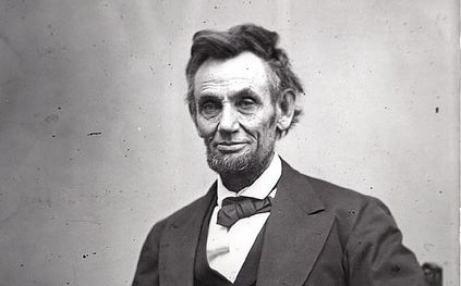 Photo: Abraham Lincoln. We see an older man with a thin face, a beard, and ruffled hair.