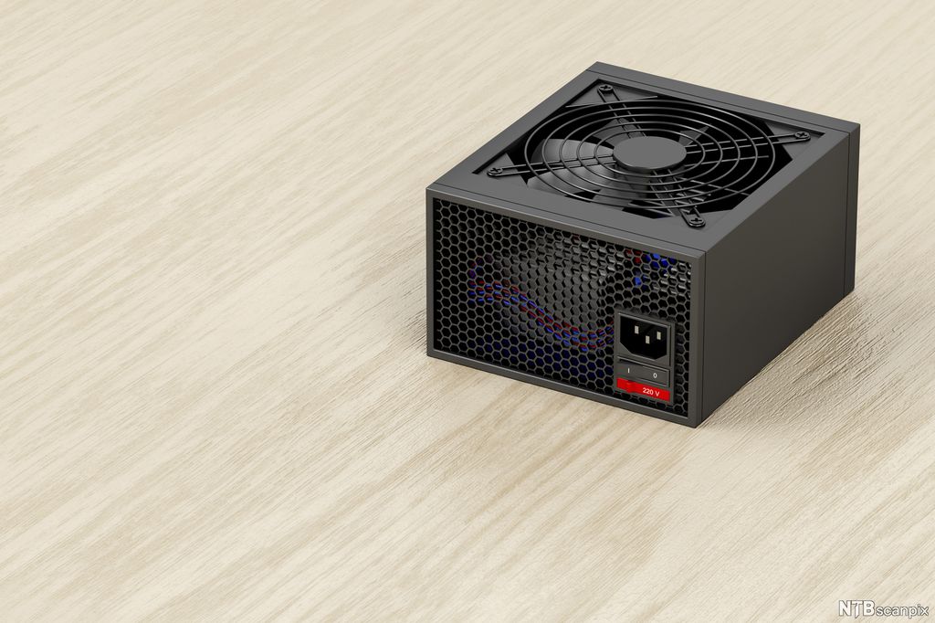 Svart boks lagd av metall, med vifte på den ene siden og kontakt for å koble til strøm på en annen. Foto.