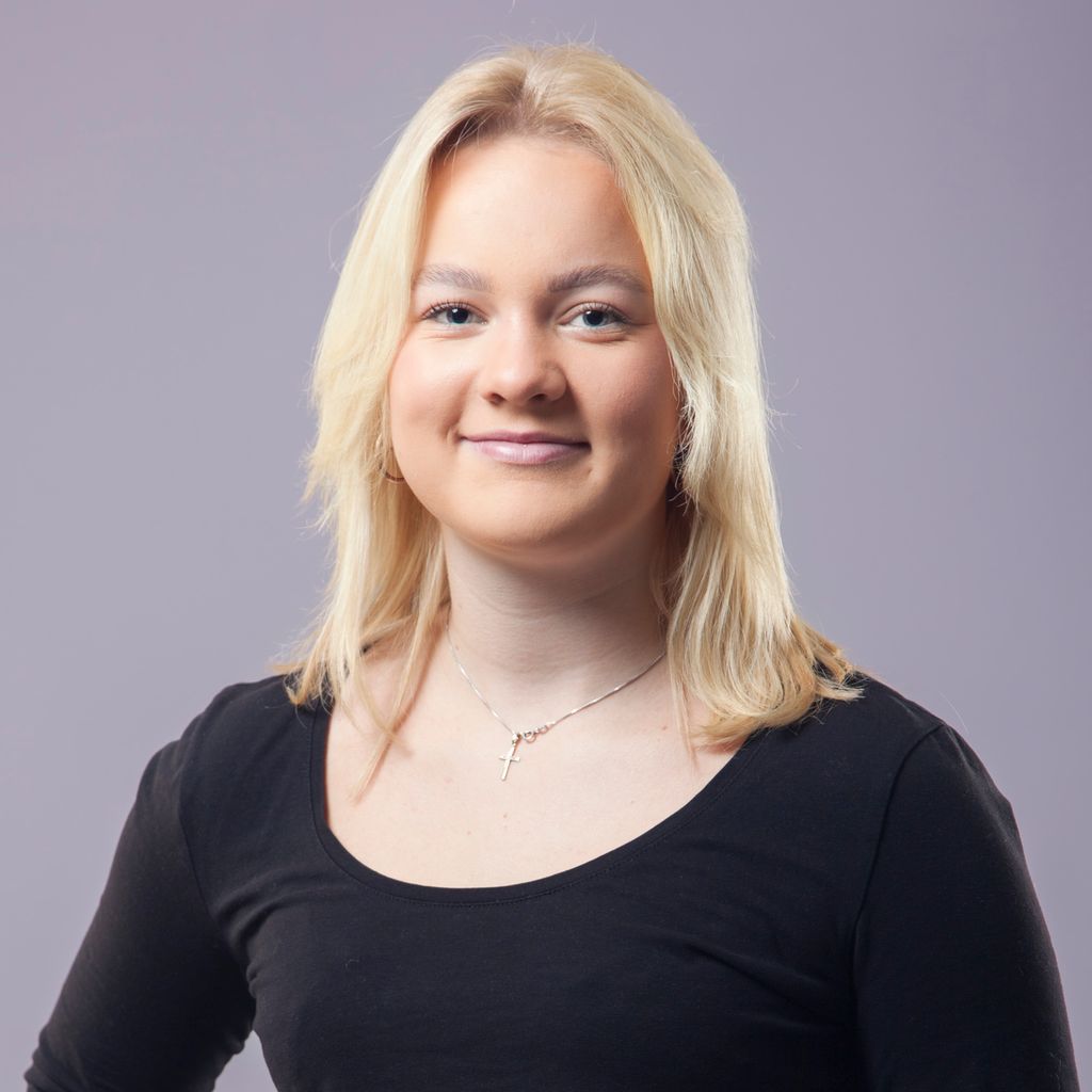 Portrait of a teenage girl with blond hair and a necklace with a cross pendant. Photo. 