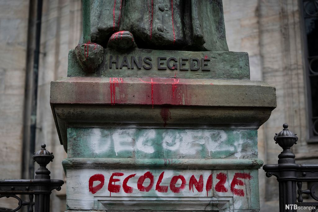Sokkelen til statuen av Hans Egede med ordet "decolonize" sprayet på med rød maling. Foto.
