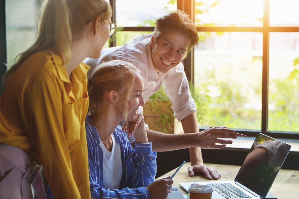 Elever jobber sammen i et klasserom. Fire elever i forgrunnen av bildet. To av dem viser to andre elever hva de holder på med på dataskjermen. Foto.
