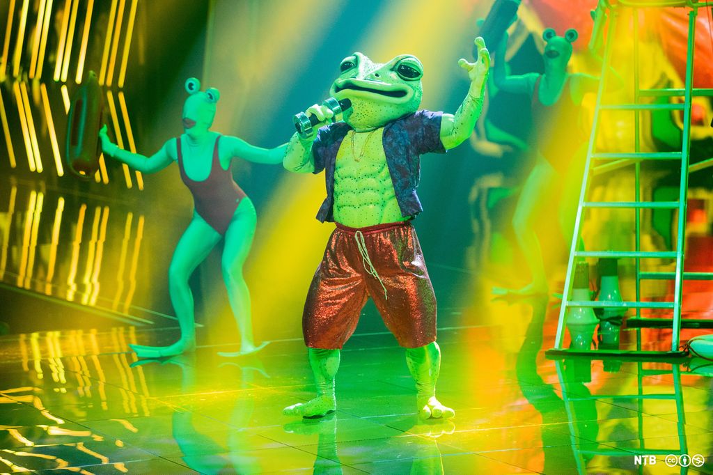 En person utkledd som frosk synger på scenen i tv-programmet Maskorama.