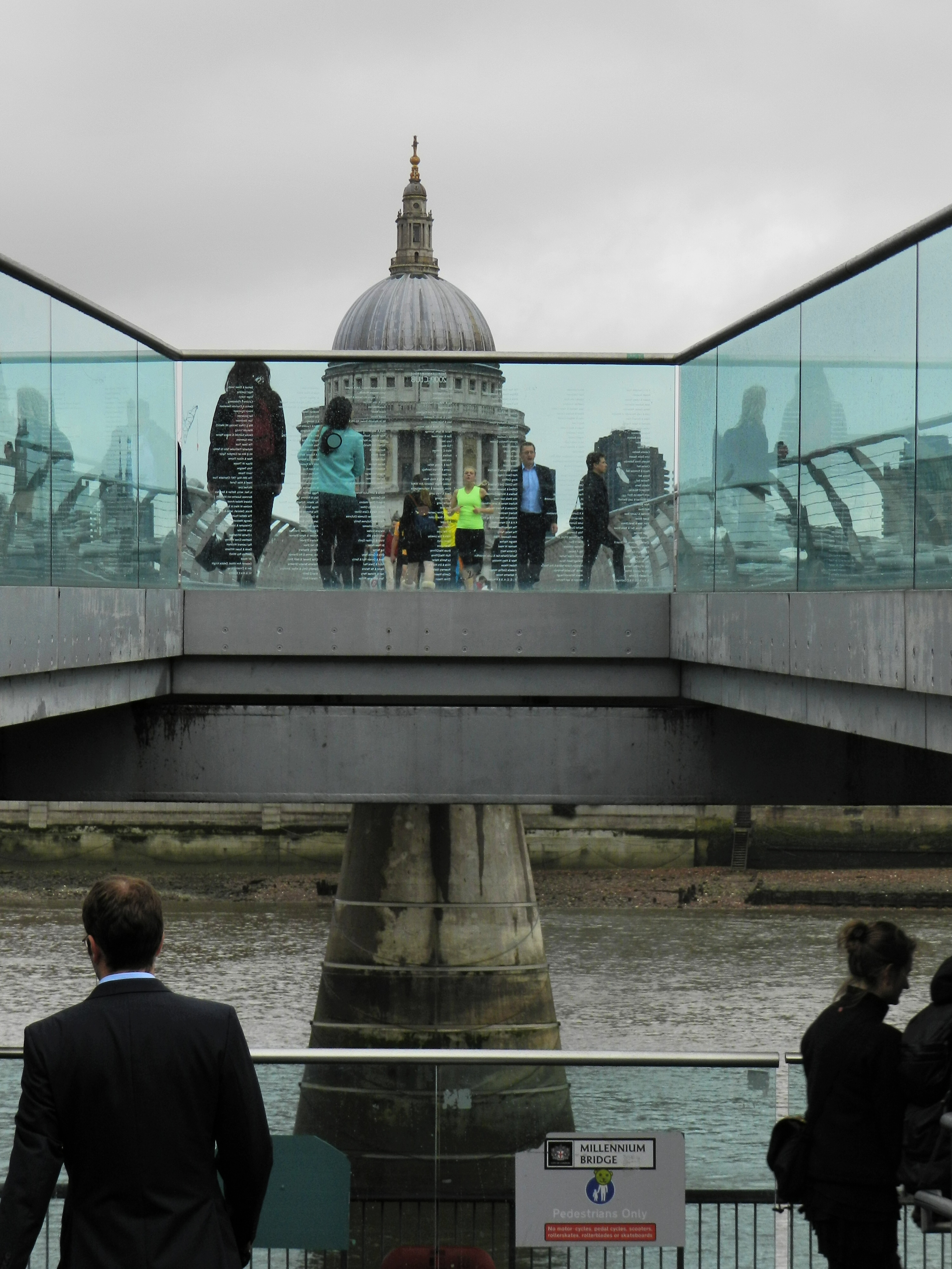 People walking on a bridge, St. Paul's Cathedral in the background. Photo.