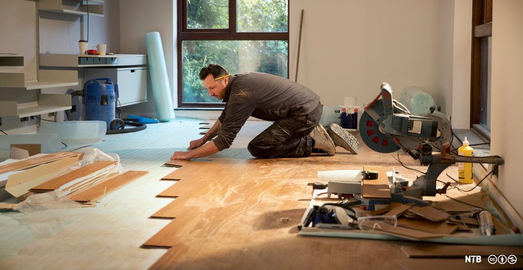Mann legger parkettgulv. Foto.